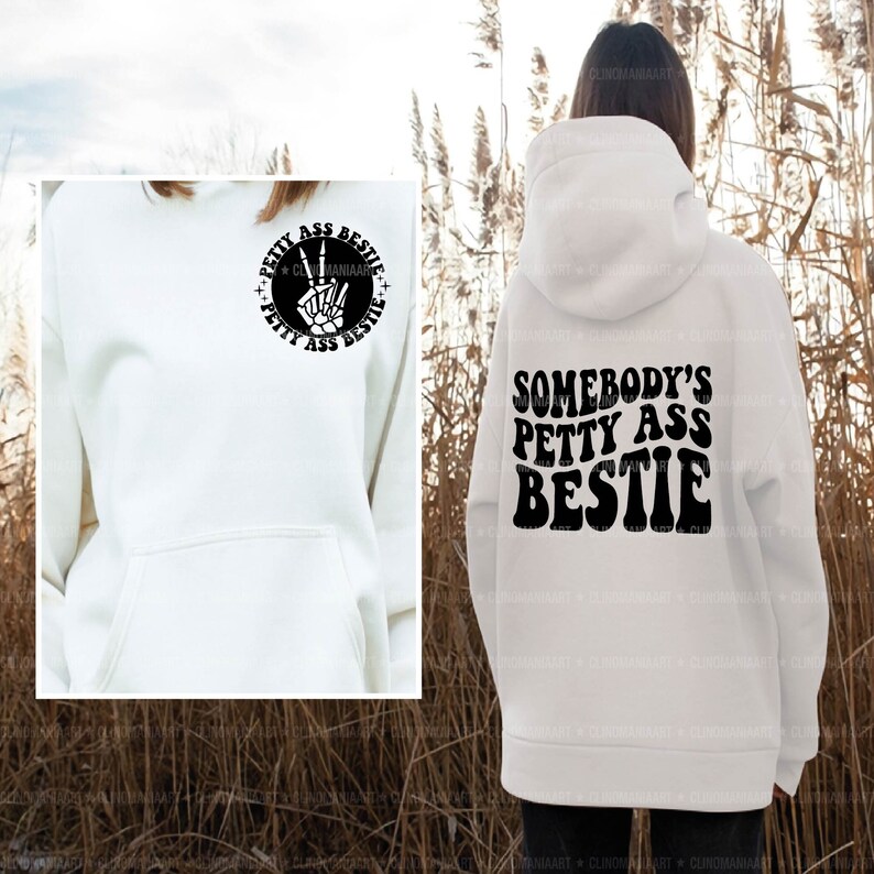 Op de afbeelding: Witte hoodie met een zwarte grafische print op de rug die "Somebody's Petty Ass Bestie" zegt. De voorkant van de hoodie heeft een kleinere zwarte grafische print die "Petty Ass Bestie" zegt met een vredesteken.