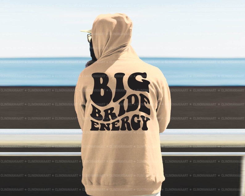 K&ouml;nnte beinhalten: Ein beiger Hoodie mit einem schwarzen Aufdruck auf der R&uuml;ckseite, der "Big Bride Energy" lautet.