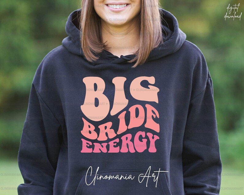 K&ouml;nnte beinhalten: Schwarzer Hoodie mit einem pinkfarbenen und orangenen Aufdruck, der "Big Bride Energy" und "Cinomania Art" in wei&szlig;er Schrift zeigt.
