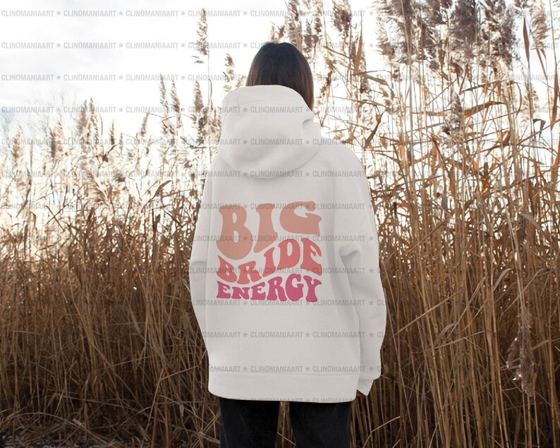 K&ouml;nnte beinhalten: Wei&szlig;er Hoodie mit einem pinkfarbenen und orangenen Aufdruck, der auf der R&uuml;ckseite "Big Bride Energy" lautet.