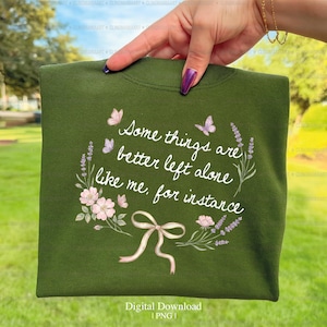 Puede incluir: Una sudadera verde oscuro con la frase "Some things are better left alone like me, for instance" en escritura blanca. El diseño incluye lavanda, flores rosas, mariposas y un lazo.