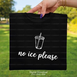 May include: Black sweatshirt with a white graphic of a drink cup with a straw and the words "no ice please". The sweatshirt is held up by a hand with a gold chain bracelet and purple nail polish.