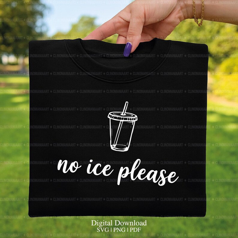 May include: Black sweatshirt with a white graphic of a drink cup with a straw and the words "no ice please". The sweatshirt is held up by a hand with a gold chain bracelet and purple nail polish.