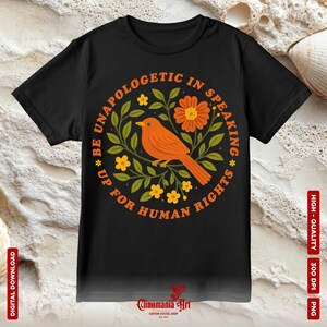May include: Black t-shirt featuring a circular design with an orange bird, flowers, and the text "BE UNAPOLOGETIC IN SPEAKING * UP FOR HUMAN RIGHTS". The design is surrounded by green leaves. The words "DIGITAL DOWNLOAD", "HIGH-QUALITY", "300 DPI", and "PNG" are also visible.