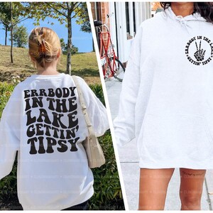 May include: White hooded sweatshirt with a black graphic print on the front. The graphic is a peace sign with the text "Errbody in the lake gettin' tipsy" around it.