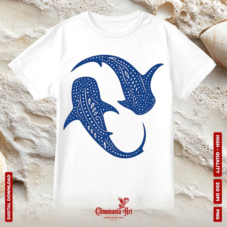 May include: A white t-shirt with a blue silhouette of two whale sharks facing each other. The whale sharks are outlined in white and have a pattern of white dots and lines. The text 'Clinomania Art' is printed in black at the bottom of the shirt.