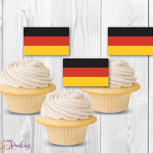 May include: Three cupcakes with white frosting and a German flag topper on each. The flag is black, red, and yellow.