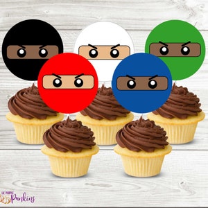 Puede incluir: Seis cupcakes con glaseado de chocolate cubiertos con adornos redondos de papel para cupcakes que representan un diseño de cara de ninja en negro, blanco, rojo, azul y verde.