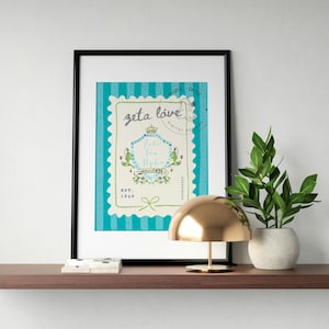 Może przedstawiać: Oprawiony wydruk z czarną obwódką z turkusowo-białym wzorem. Na wydruku widnieją słowa "zeta love" i inny tekst. Złota lampa i roślina doniczkowa stoją na brązowej półce.