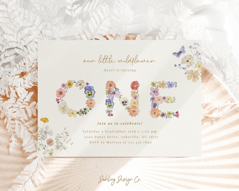 May include: A floral-themed first birthday invitation with the word "ONE" spelled out in pressed flowers. The invitation is for Hazel's birthday party on September 10th at 3:00 pm. The address is 1090 Pansy Drive, Asheville, NC 28715. RSVP to Marissa at 123.456.7890.