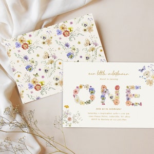 May include: A floral-themed first birthday party invitation with the word "ONE" spelled out in flowers. The invitation is decorated with a watercolor pattern of wildflowers and butterflies. The text reads "our little wildflower is turning ONE. Join us to celebrate! Saturday, September 10th, 4:00 pm 1000 Fancy Drive, Asheville, NC 28815 RSVP to Marion at 123-456-7890"