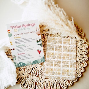 May include: A pink and white card with the text "Palm Springs Before the Rings Weekend Itinerary" and a list of activities for a weekend trip to Palm Springs, California. The card is decorated with tropical illustrations.