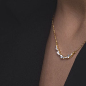 Puede incluir: Un collar de cadena de oro con una fila curva de peque&ntilde;as piedras preciosas transparentes.