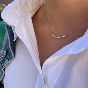 Puede incluir: Un collar de cadena de oro con una fila de peque&ntilde;os diamantes transparentes dispuestos en forma de curva.