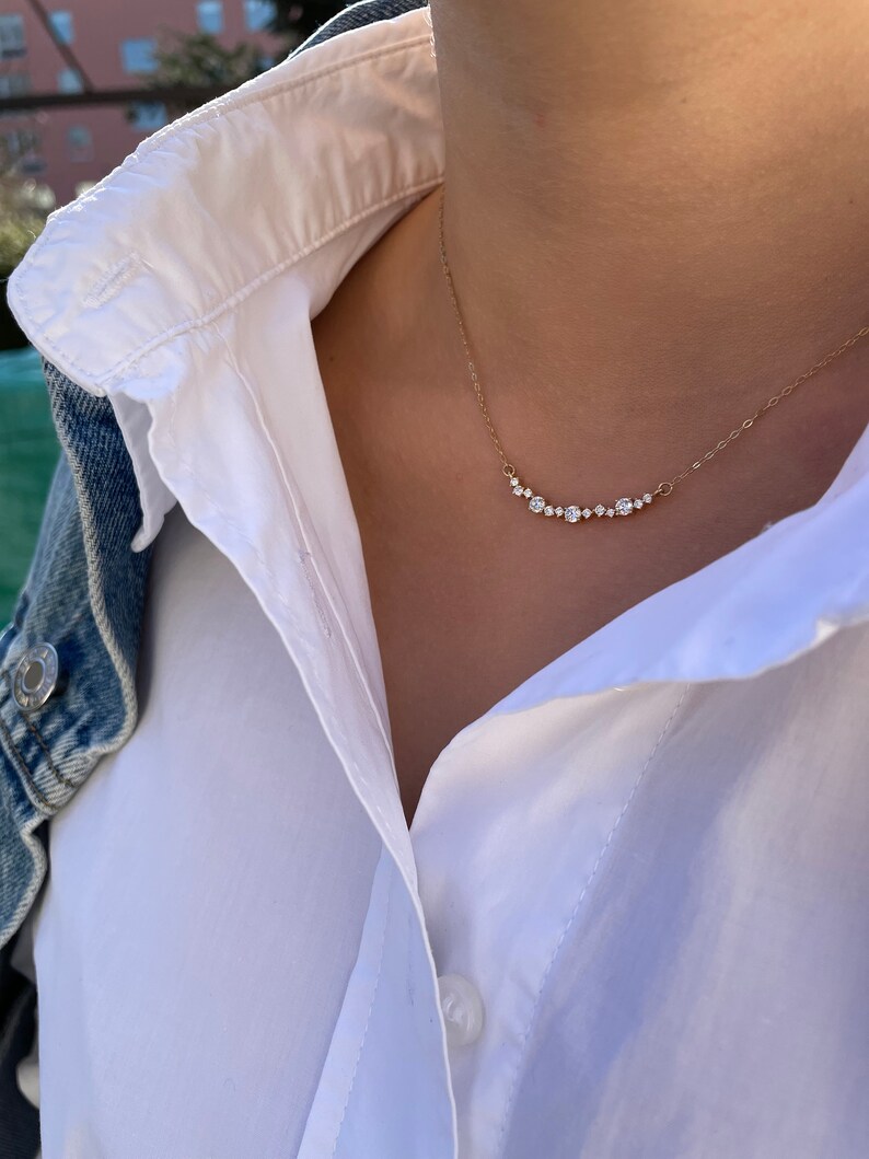 Puede incluir: Un collar de cadena de oro con una fila de peque&ntilde;os diamantes transparentes dispuestos en forma de curva.