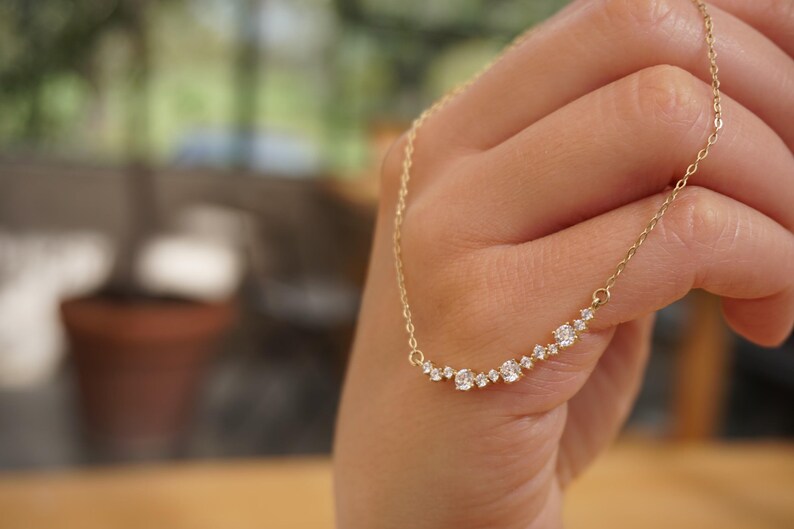Puede incluir: Un collar de oro con una l&iacute;nea curva de peque&ntilde;os diamantes.