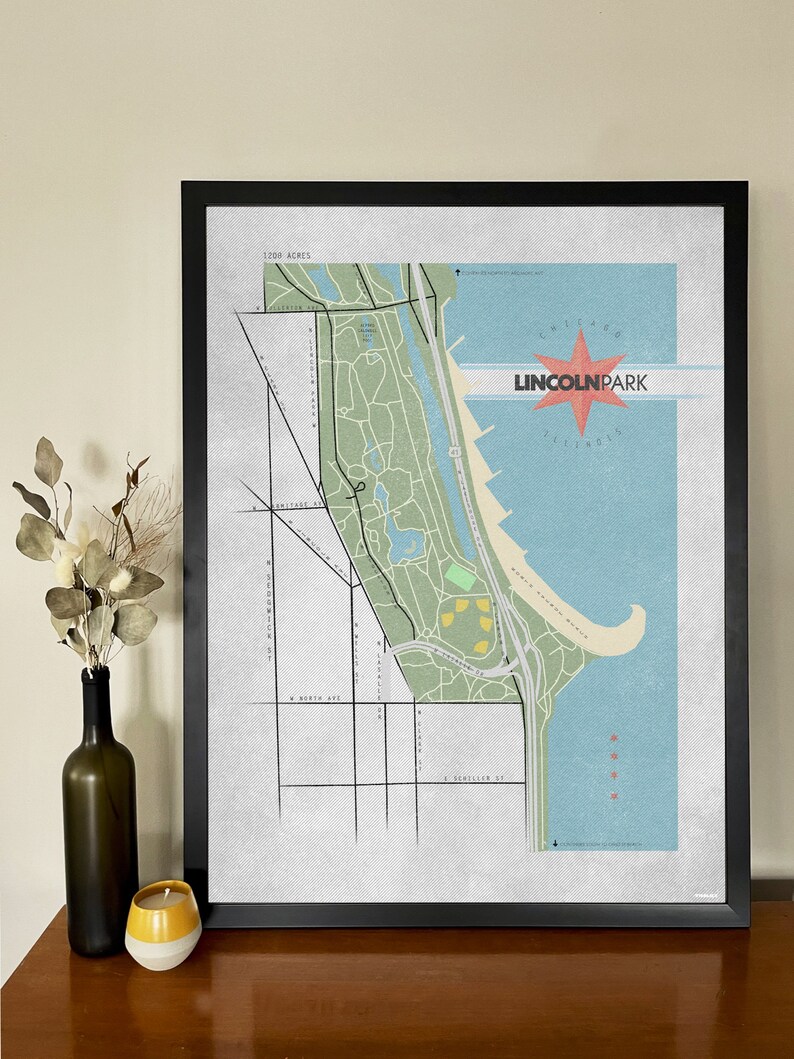 Może przedstawiać: Oprawiona grafika mapy Parku Lincolna w Chicago, z wystylizowaną ilustracją z zielonymi obszarami parku, niebieskim jeziorem i czerwoną gwiazdą z tekstem "Lincoln Park Illinois". Mapa jest w czarnej ramie.