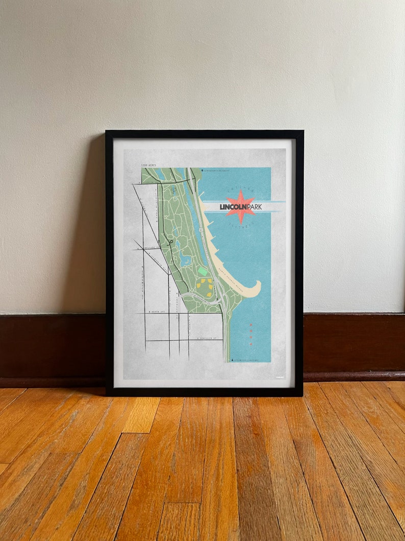 Może przedstawiać: Oprawiony wydruk mapy Lincoln Park w Chicago. Mapa przedstawia zielone tereny parkowe, niebieską wodę i stylizowaną czerwoną gwiazdę z napisem "LINCOLN PARK". Wydruk jest w czarnej ramie i spoczywa na drewnianej podłodze.