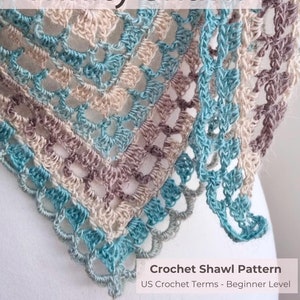 May include: A crochet shawl pattern in blue, brown, and beige colors. The pattern is called "Trinity Shawl" and is written in US crochet terms for beginners.
