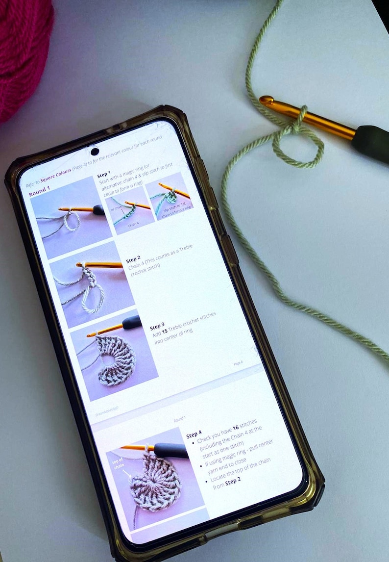 May include: A close-up of a phone screen showing instructions for crocheting a round object. The instructions are broken down into four steps, with images of each step. The text on the screen reads "Refer to Square Colours Page 61 for the relevant colour for each round. Round 1. Step 1. Start with a magic ring for alternative chain & slip stitch to first chain to form a ring. Step 2. Chain 4 (This counts as a Treble crochet stitch). Step 3. Add 15 Treble crochet stitches into center of ring. Step 4. Check you have 16 stitches (including the Chain 4 at the start as one stitch). If using magic ring - pull center yarn end to close. Locate the top of the chain from Step 2."