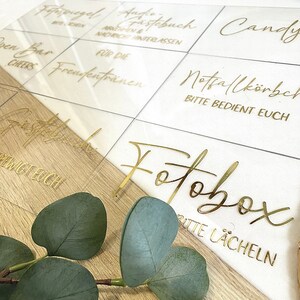 Könnte beinhalten: Ein Satz durchsichtiger Acrylschilder mit goldener Beschriftung. Die Schilder haben verschiedene Sätze darauf geschrieben, darunter "Gästebuch", "Fotobox", "Süßigkeiten", "Offene Bar", "Prost", "Für die Freudian", "Notfallkörbchen", "Bitte bedient euch" und "Fopspiegel".