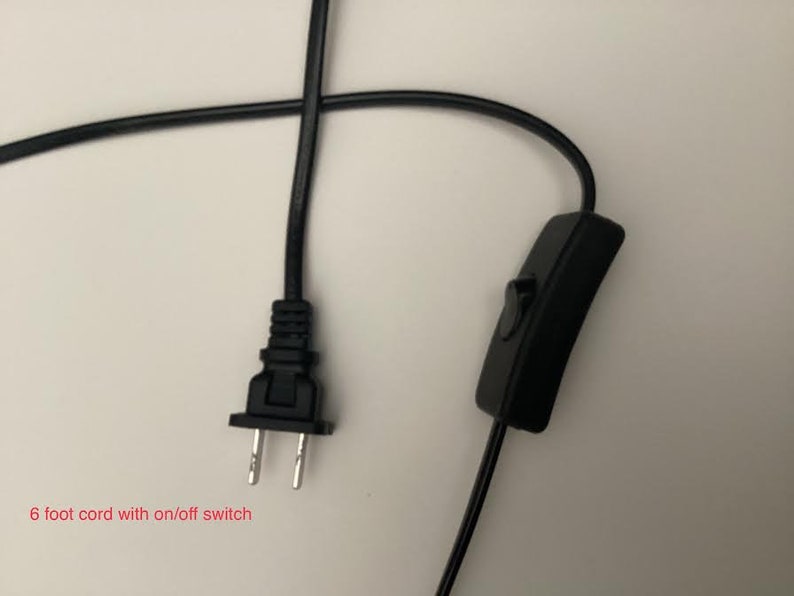 K&ouml;nnte beinhalten: Schwarzes Elektrokabel mit einem Zweipolstecker und einem Ein-/Ausschalter. Der Text im Bild lautet: "6 Fu&szlig; Kabel mit Ein-/Ausschalter." Das Kabel ist etwa 183 cm lang.