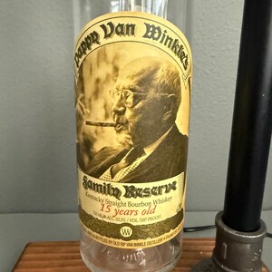 K&ouml;nnte beinhalten: Eine klare Glasflasche Pappy Van Winkle's Family Reserve Kentucky Straight Bourbon Whiskey. Das Etikett zeigt ein Sepia-Portr&auml;t eines Mannes, der eine Zigarre raucht. Der Text lautet "15 Jahre alt" und "750 ml".