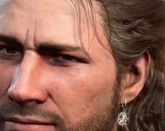 May include: A close-up portrait of a man with long, wavy brown hair and a short beard. He wears a silver earring with a starburst design. The man has a serious expression.