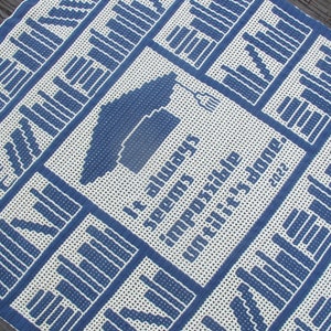 Puede incluir: Una manta de crochet blanca y azul con un diseño de gorro de graduación y la cita "Siempre parece imposible hasta que se hace." 2022.