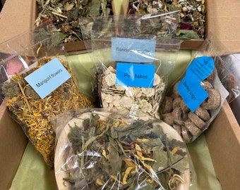 May include: A cardboard box filled with various dried herbs and flowers, including dandelion, marigold, and barley rings. The box is labeled "Puffy Tails" and includes a note that says "Handmade with Love in the UK".