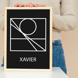 May include: A black and white geometric design with a circle and lines in a square frame. The design is on a black background with a white wooden frame. The word "XAVIER" is printed in white at the bottom of the frame.