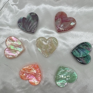 May include: Seven iridescent heart-shaped decorative pieces in various shades of pink, green, and purple.