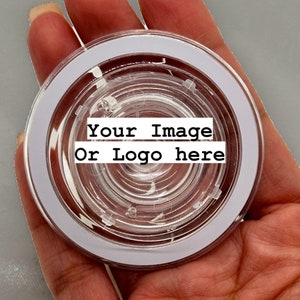May include: A clear, circular product with a white border, held in a hand. The center of the product has a spiral design. Text on the product reads "Your Image Or Logo here".
