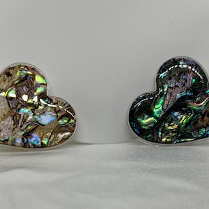 May include: Four iridescent abalone shell jewelry pieces in different shapes, including a round, heart, and two heart shapes.