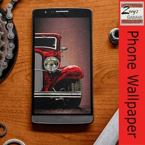 Può includere: Primo piano di un'auto d'epoca rossa con dettagli cromati, visualizzata sullo schermo di uno smartphone. L'auto è una hot rod classica con un'illustrazione dettagliata della griglia anteriore e dei fari.