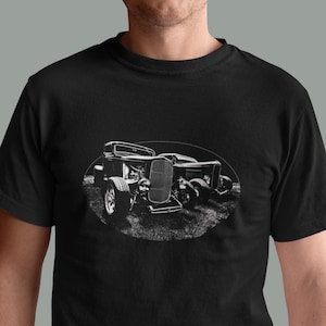 May include: A black t-shirt with a white graphic of two vintage hot rods. The hot rods are facing forward and are in an oval shape.