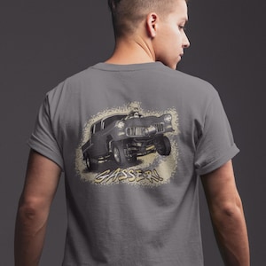 May include: A grey t-shirt featuring a black and white illustration of a vintage hot rod car with the word "GASSER!" printed on the back.