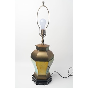 May include: A vintage brass table lamp with an octagonal base and a matching shade. The lamp has a bulb and a black cord. The lamp is a decorative lighting fixture.