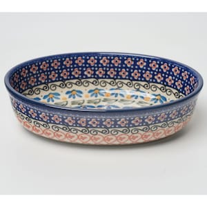 May include: A round ceramic serving bowl with a dark blue rim and floral patterns. The bowl features a repeating pattern of small flowers and dots in shades of blue, orange, and pink. The interior has a floral design with blue and yellow flowers.