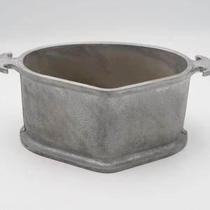 May include: A silver-colored, triangular-shaped metal container with two decorative handles. The container has a textured surface and a wide opening. The base of the container is slightly raised.