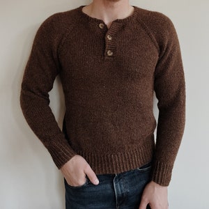 May include: A brown knitted sweater with a button-up collar. The sweater has a ribbed texture and a relaxed fit.