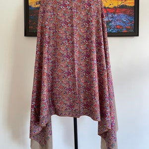 May include: A brown shawl with a floral pattern in shades of pink, blue, and orange. The shawl is made of a soft, lightweight fabric and has a fringed edge.