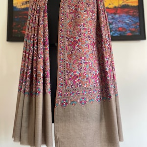 May include: A brown shawl with a floral pattern in shades of pink, blue, and orange. The shawl has a border with a paisley design.
