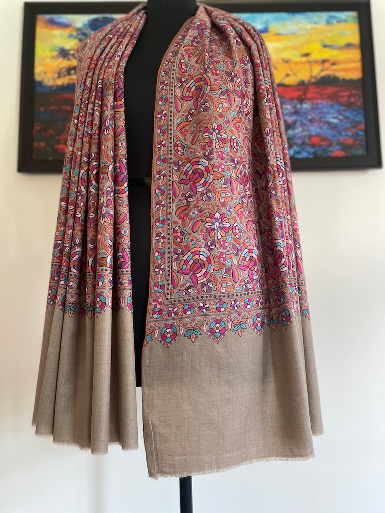 May include: A brown shawl with a floral pattern in shades of pink, blue, and orange. The shawl has a border with a paisley design.
