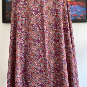 May include: A brown shawl with a floral pattern in shades of pink, blue, and orange. The shawl has a decorative border.