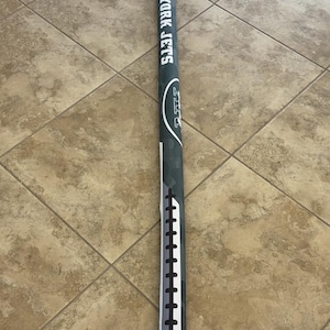 May include: A long, cylindrical, green and white sports item with the text "NEW YORK JETS" printed vertically. The item has a football-like design with white stitching and a drawstring closure. The overall design is a camouflage pattern.