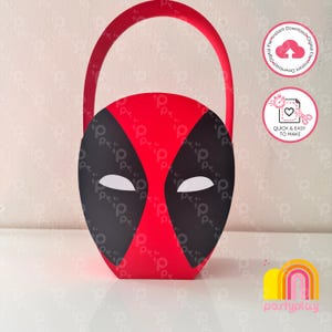 Può includere: Un cestino di carta rosso e nero con l'iconico design della maschera di Deadpool, toppe oculari bianche e un manico curvo. Il cestino presenta una stampa grafica del volto del personaggio sul davanti, con sezioni rosse e nere ben definite.