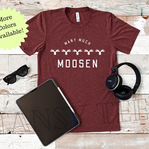 May include: A maroon t-shirt with a white graphic that says "Many Much Moosen" with a row of moose antlers above the text.