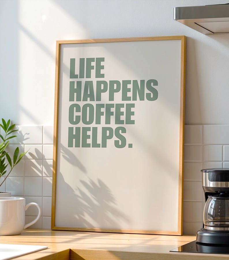May include: A framed print with the text "LIFE HAPPENS COFFEE HELPS." in green lettering on a cream background.
