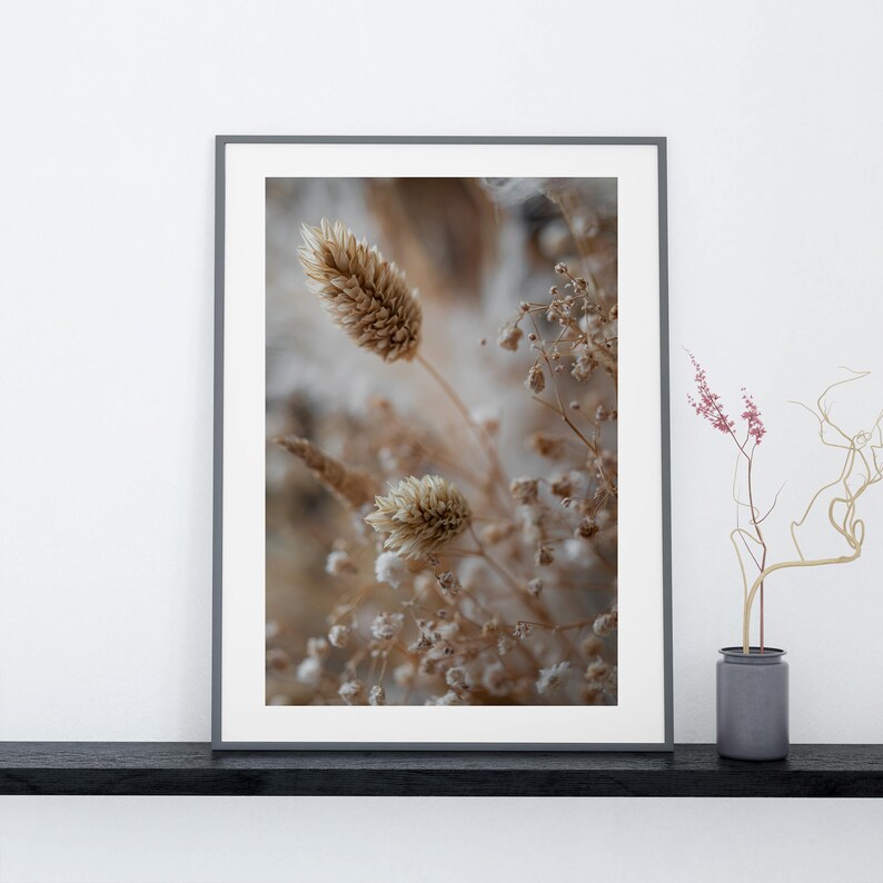 Puede incluir: Una impresi&oacute;n enmarcada de flores secas en tonos beige y marr&oacute;n. Las flores est&aacute;n dispuestas en un jarr&oacute;n y est&aacute;n rodeadas de un fondo blanco.